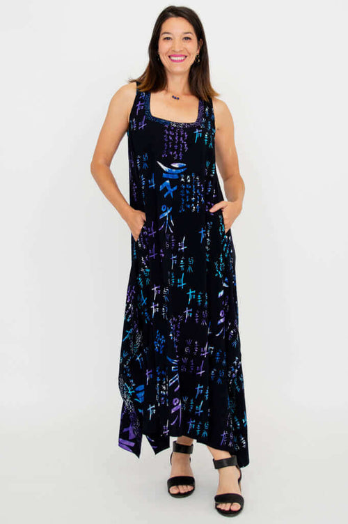 Front view of woman wearing a long, sleeveless handkerchief dress with geometric blue and purple print