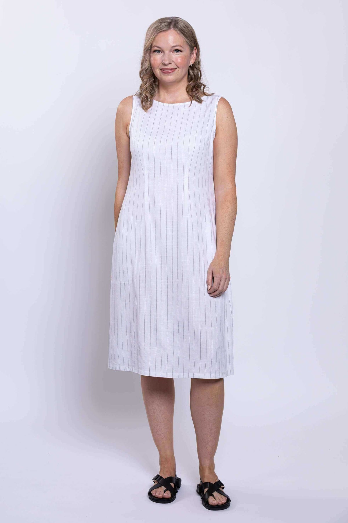 Front view of woman wearing sleeveless white dress with subtle vertical stripes