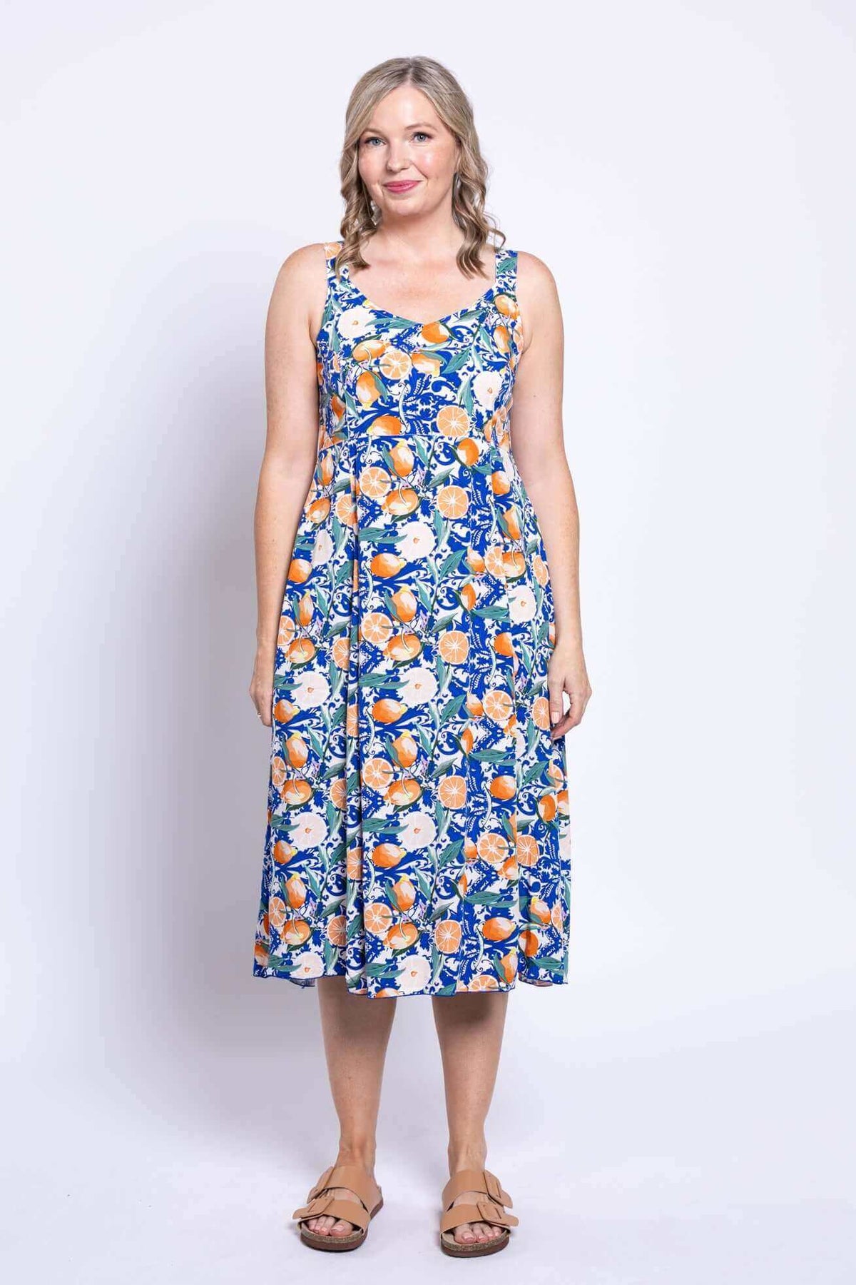 Front view of a woman wearing a sleeveless dress with a vibrant citrus floral print