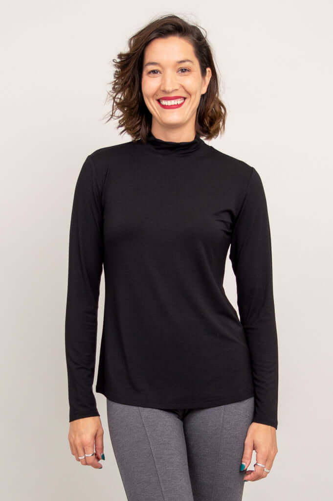 Front view of a woman wearing a black mock neck long sleeve top and gray pants