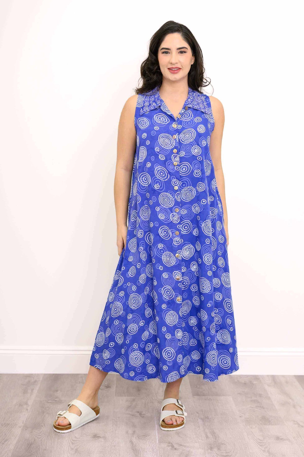 Front view of model wearing a sleeveless blue A-line dress with white circle patterns