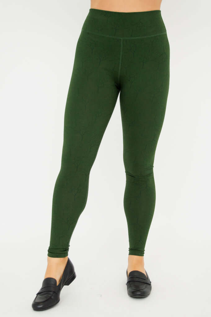 Front view of a model wearing green Riley leggings with tree-pattern texture