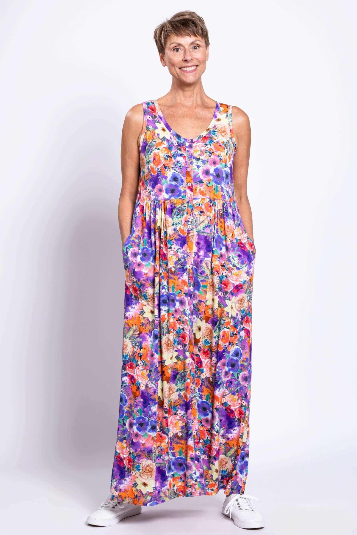 Front view of woman wearing a sleeveless colorful floral button-down maxi dress with pockets