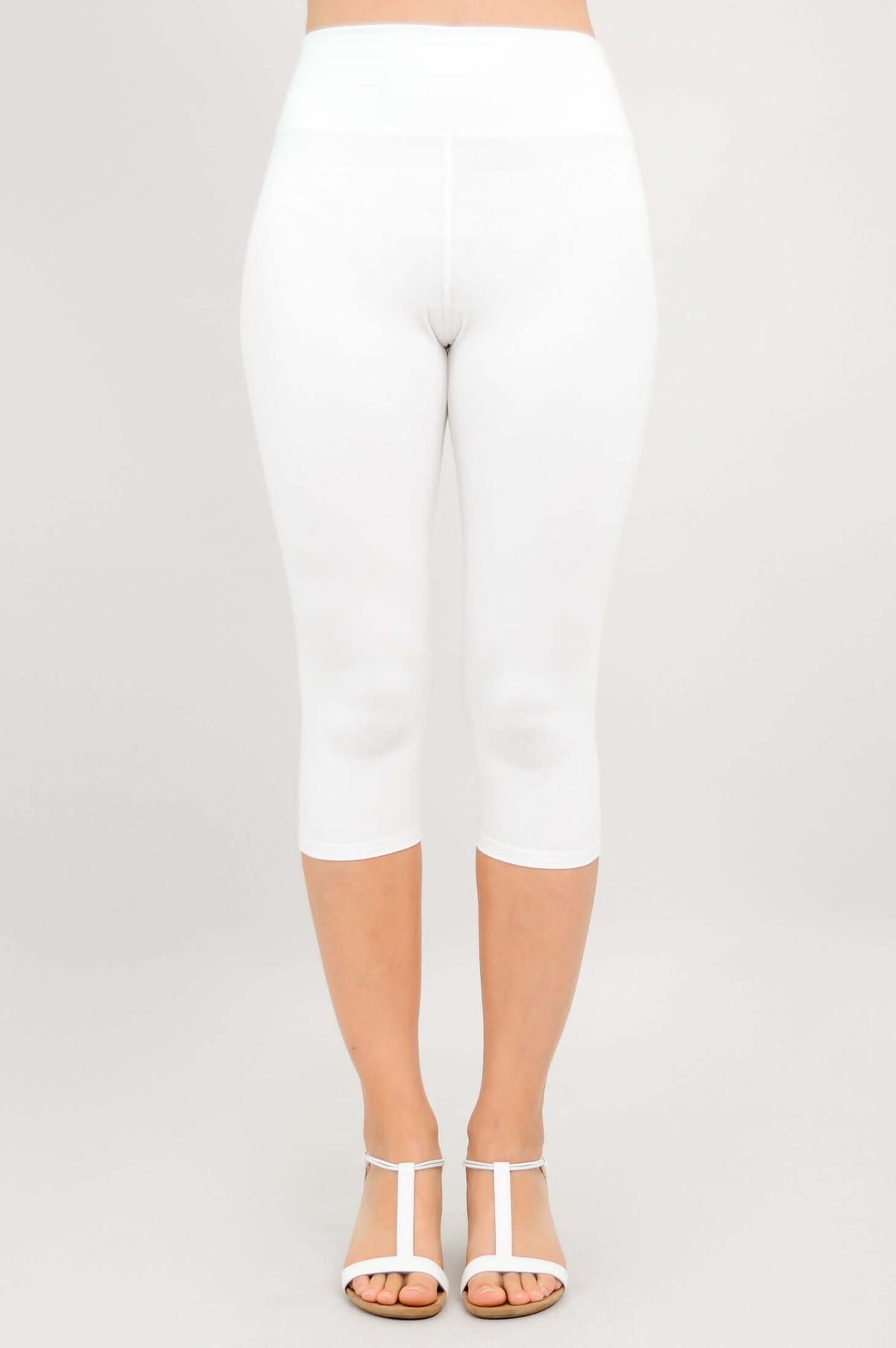 Front view of model wearing white capri leggings and white sandals