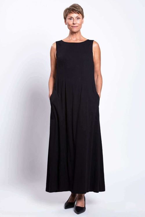 Front view of woman in black ankle-length dress, hands in pockets