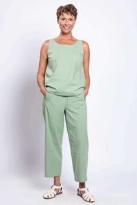 Woman wearing a sleeveless green linen top and cropped boardwalk pants, front view with hands in pockets