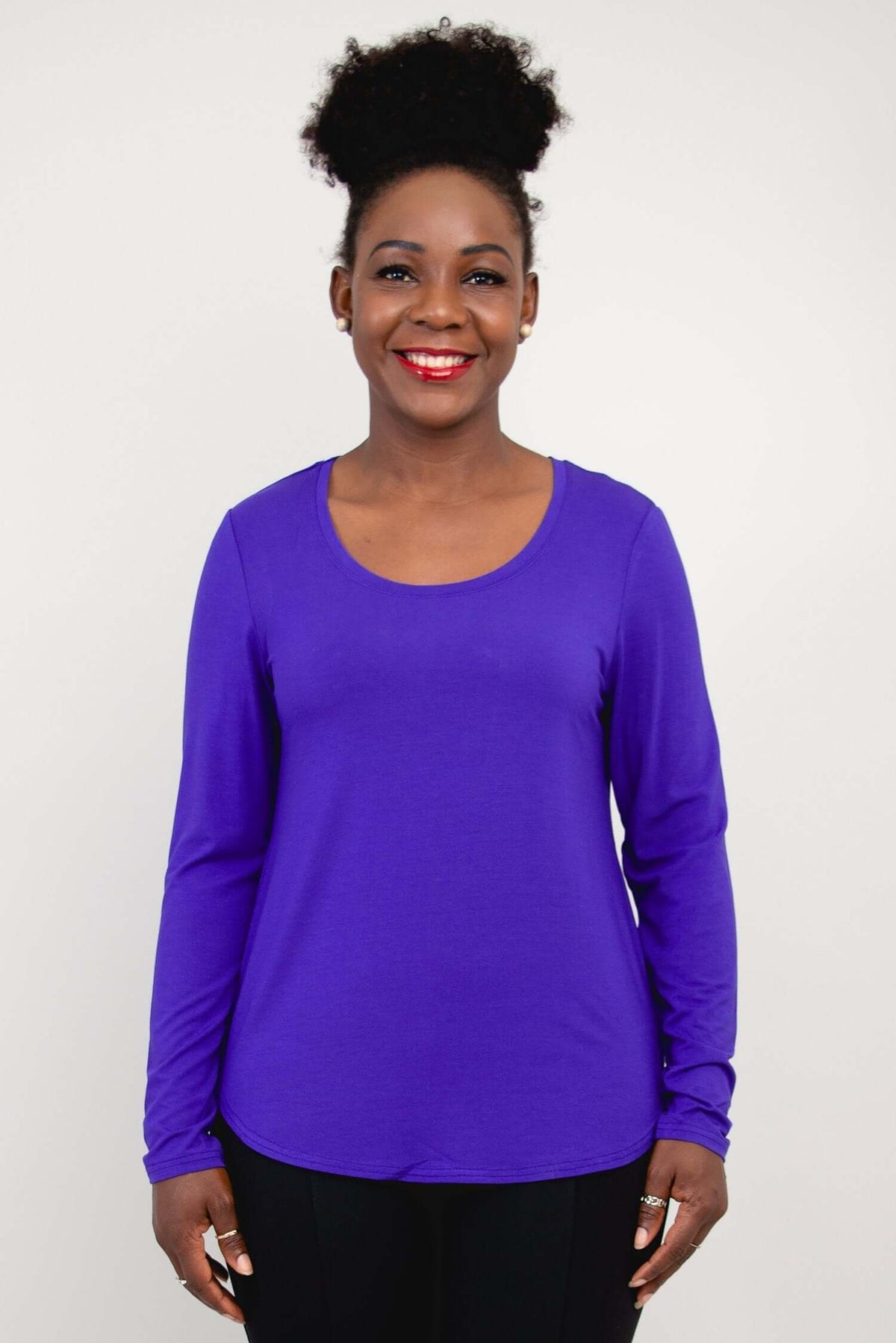 Front view of woman wearing a vibrant purple long sleeve scoop neck top