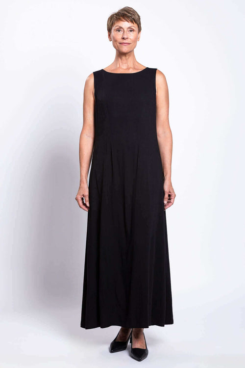 Front view of woman wearing a sleeveless black shift maxi dress with boat neck