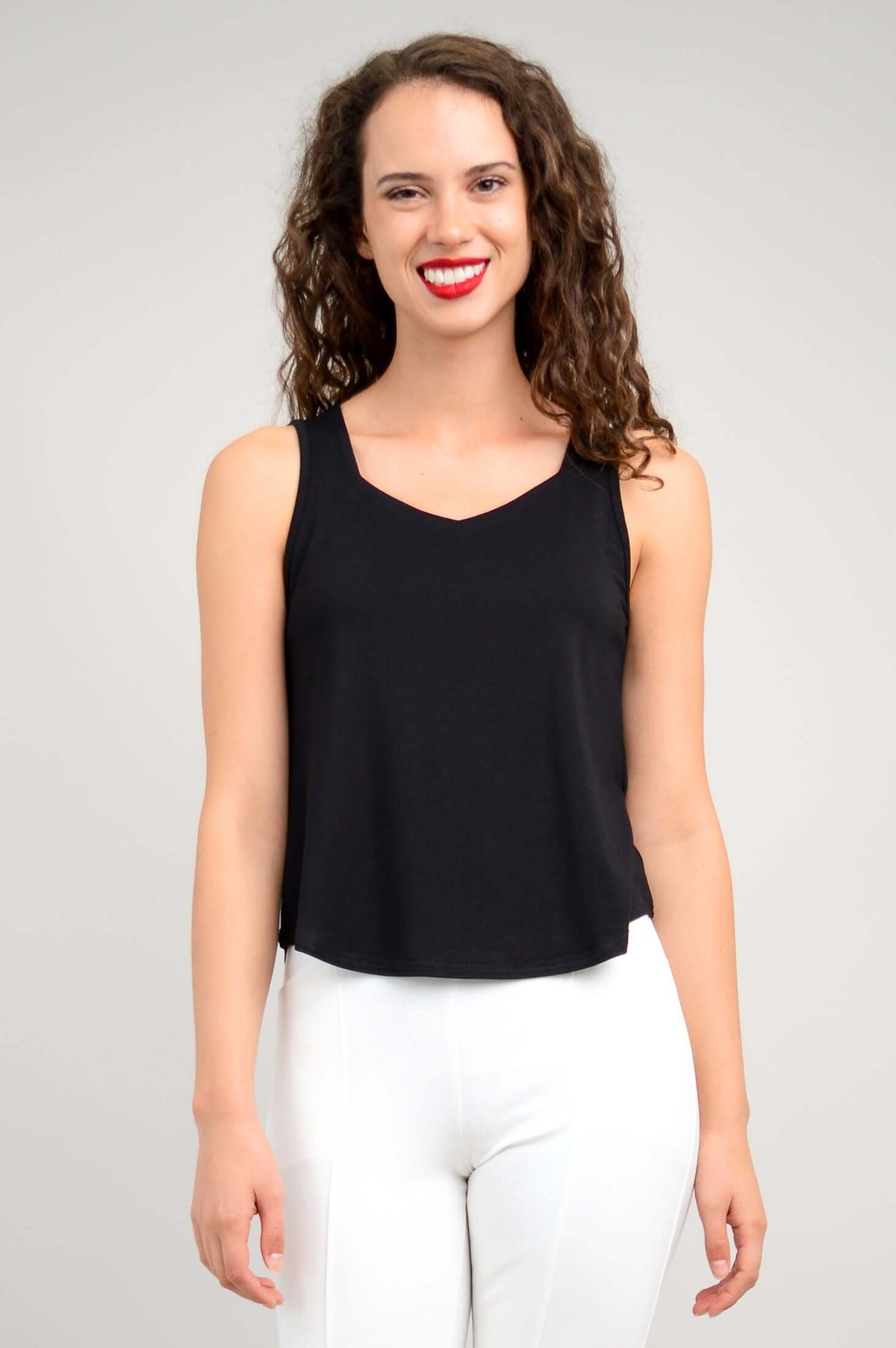 Front view of a woman wearing a sleeveless black tank top and white pants