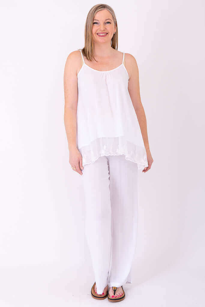 Full-length view of a woman in a white lace tank top and white pants