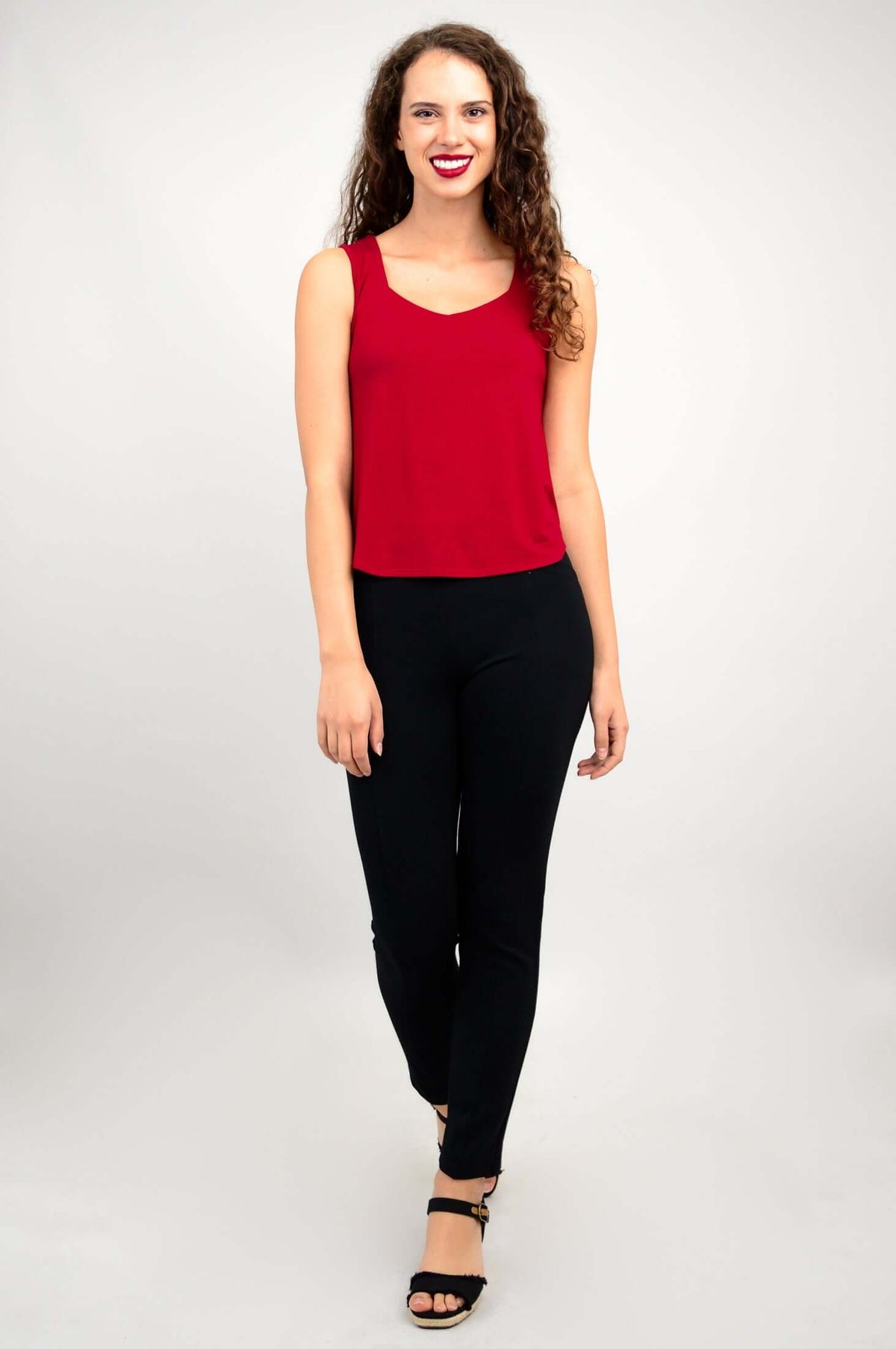 Woman in red tank top and black pants, full-body front view