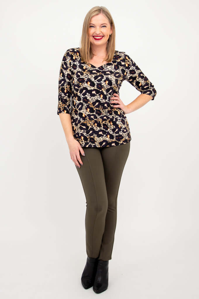 Full body view of woman in leopard print long sleeve top and olive pants
