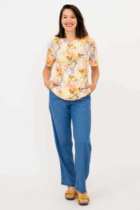 Full body view of woman in a bird print short sleeve tee and blue jeans, standing