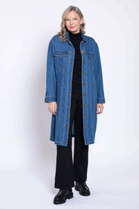 Woman modeling a longline blue denim jacket featuring button cuff sleeves and black trousers.