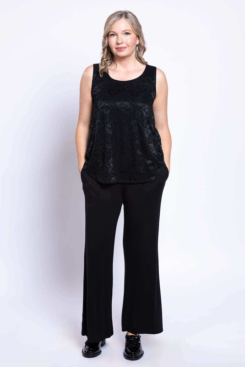 Full body front view of woman in black lace tank top and wide-leg black pants