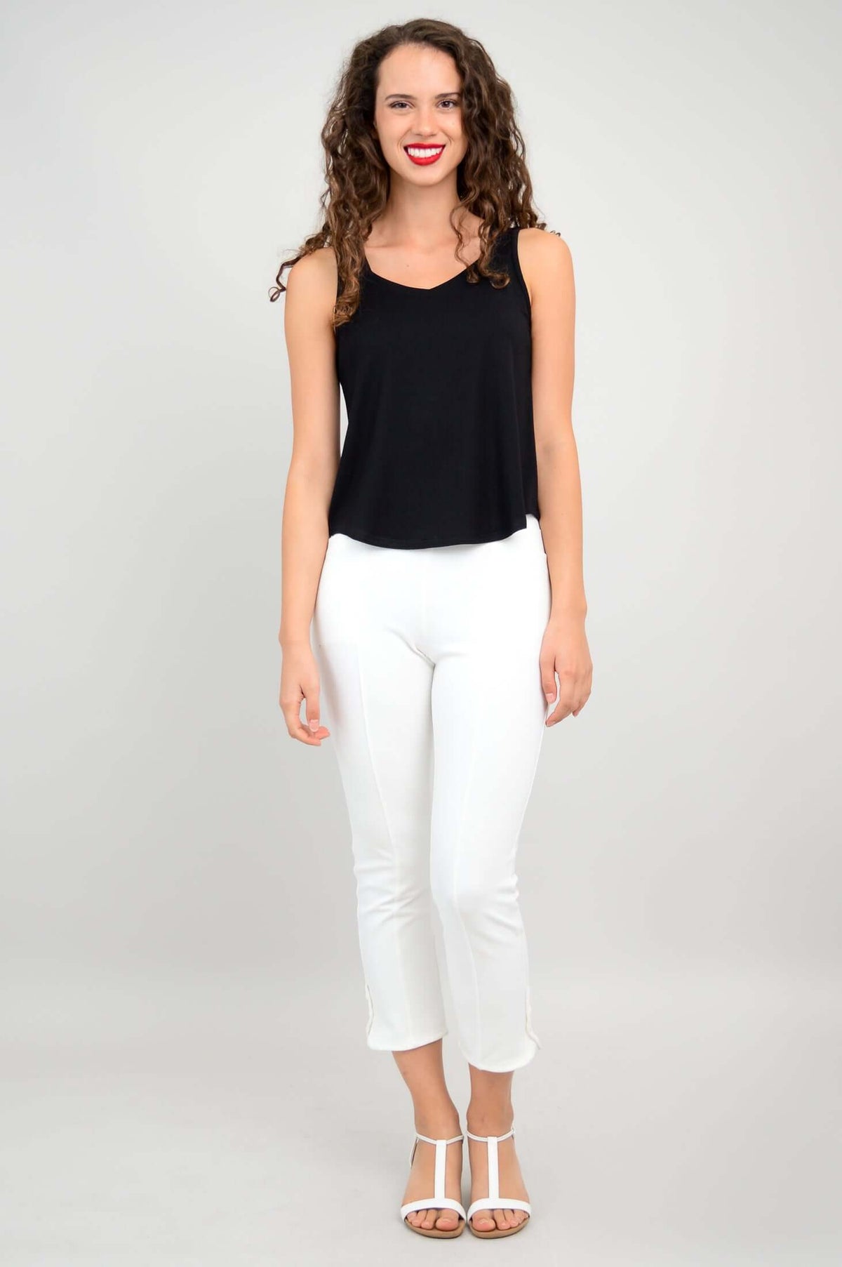 Full body view of a woman in a black tank top paired with white pants and sandals