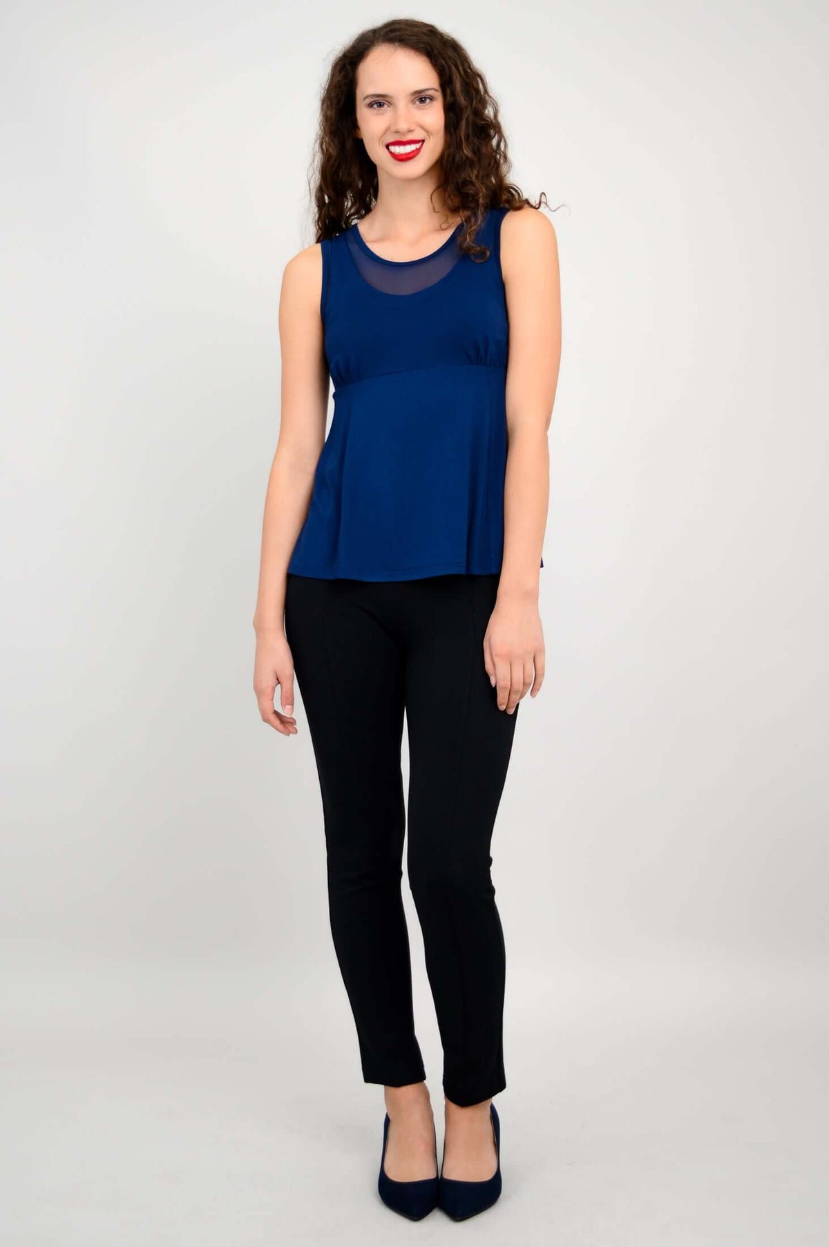 Full body view of woman in navy tank top and black pants, standing straight