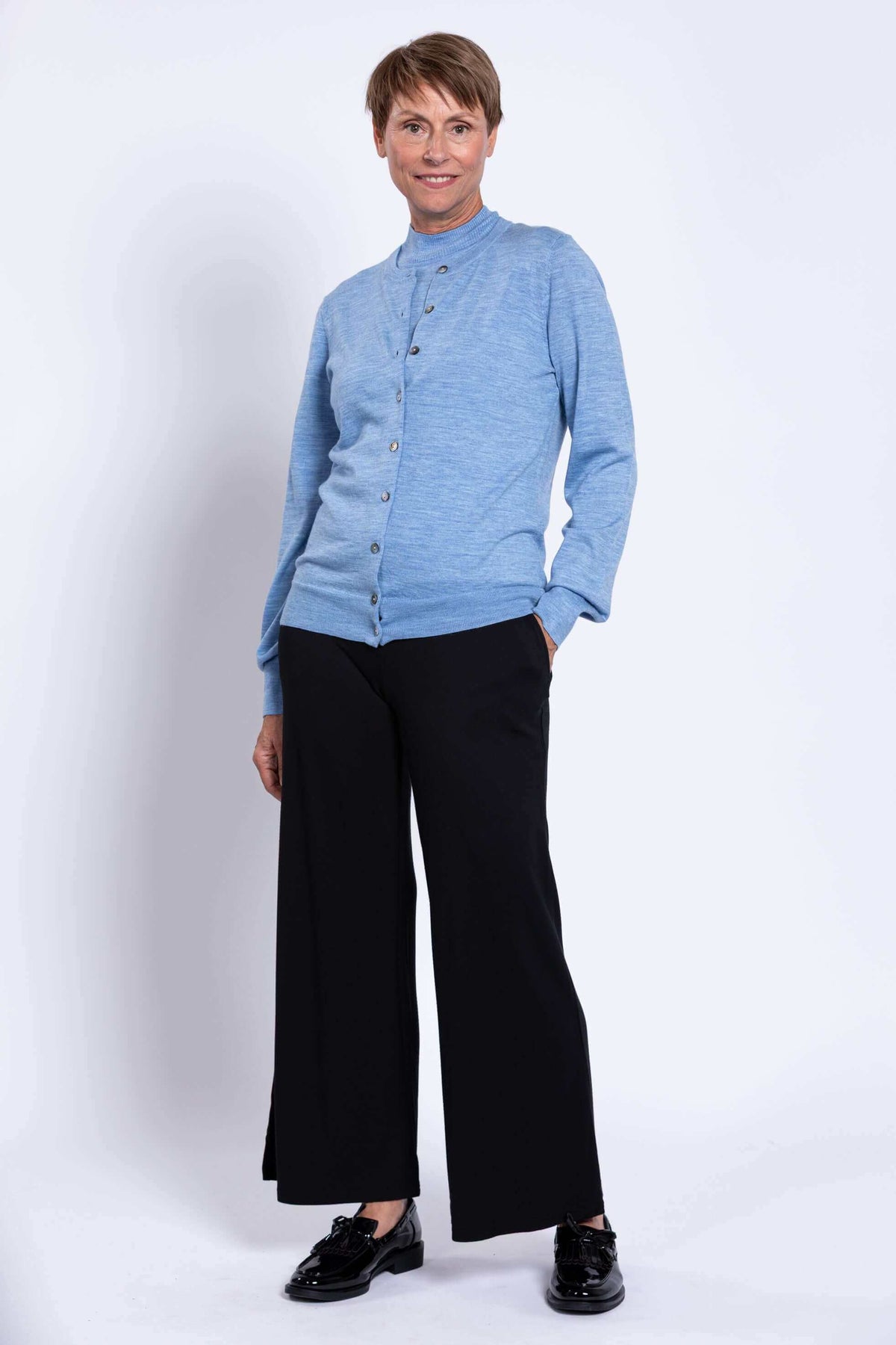 Full body view of woman in light blue cardigan and black wide-leg pants