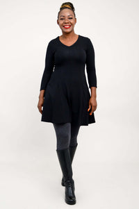 Full body view of model in black tunic dress with grey leggings and black boots