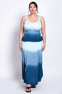 Woman standing in a blue ombre maxi dress with side slits