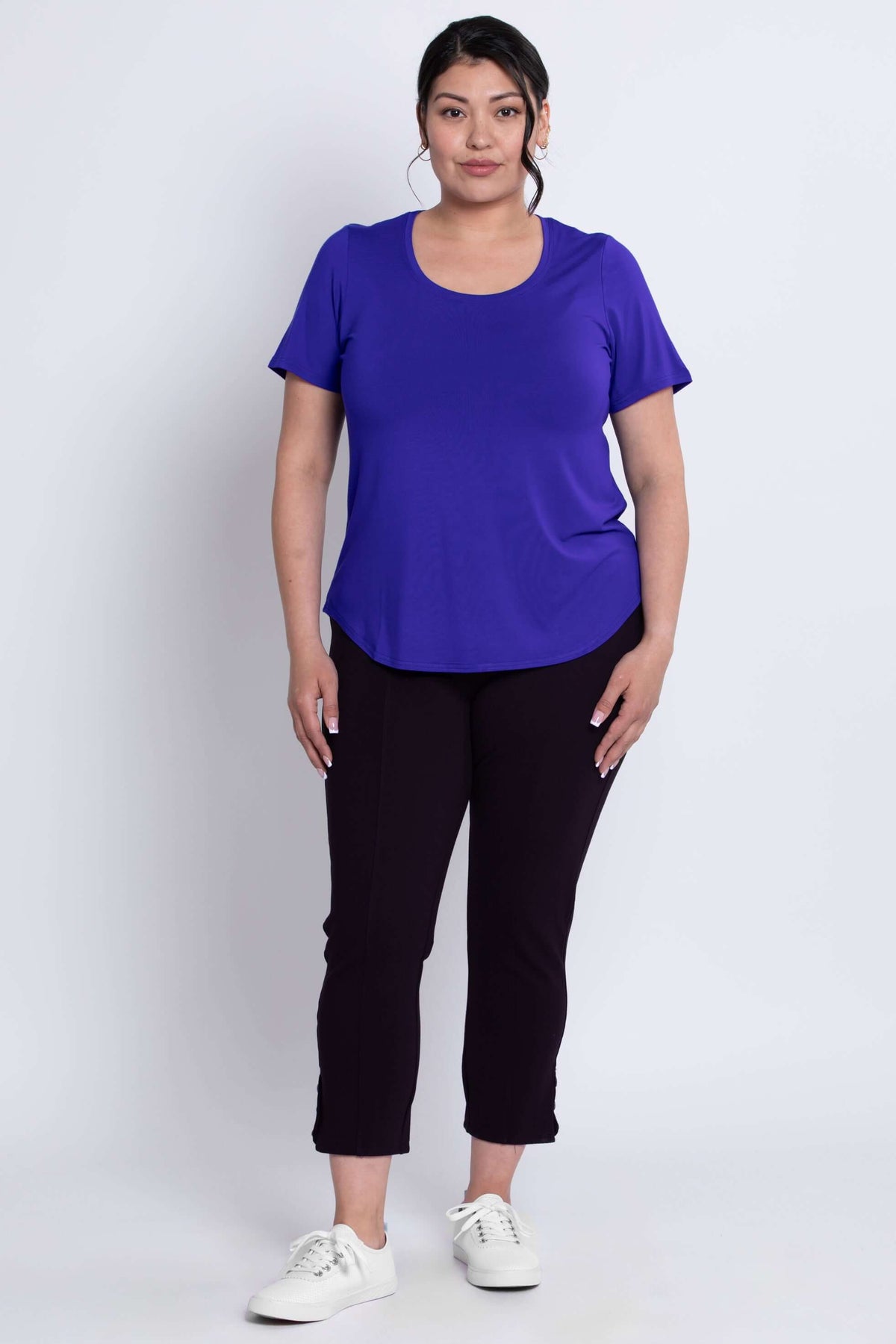 Full front view of a woman in a purple scoop neck short sleeve tee and black pants