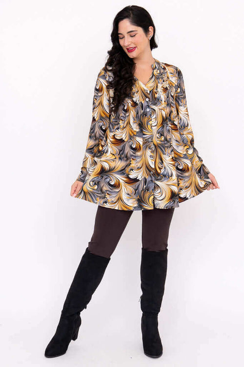 Woman modeling swirl print blouse outfit with leggings and black boots