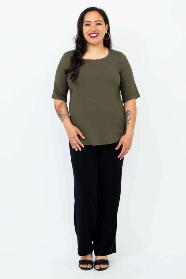 Full body view of woman wearing olive green blouse and black pants