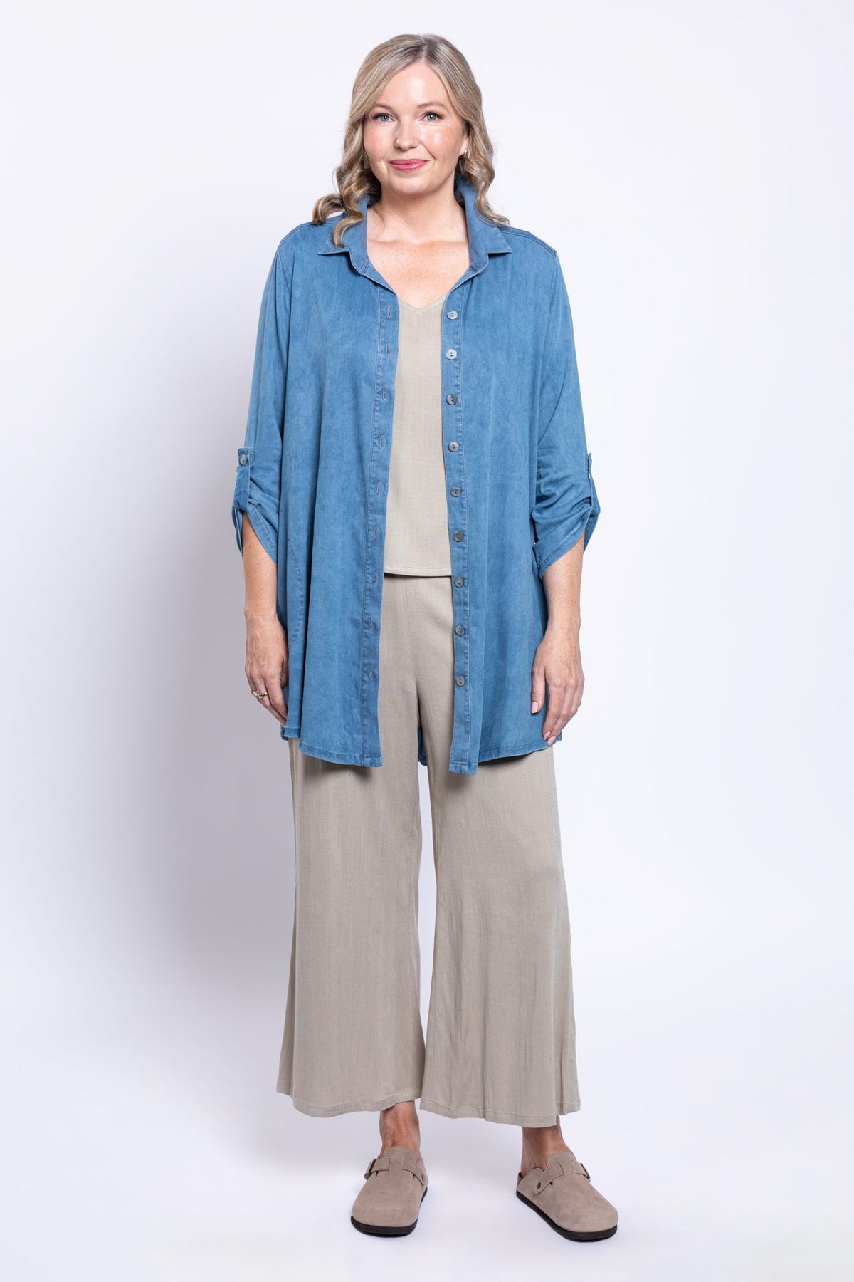 full body front view of woman wearing unbuttoned tencel denim shirt over a beige outfit
