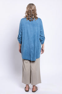 Back view of woman modeling tencel denim tunic in light blue and wide-leg beige pants