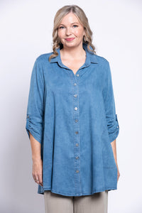 Woman wearing a blue denim shirt with gathered sleeves and collar against a white background