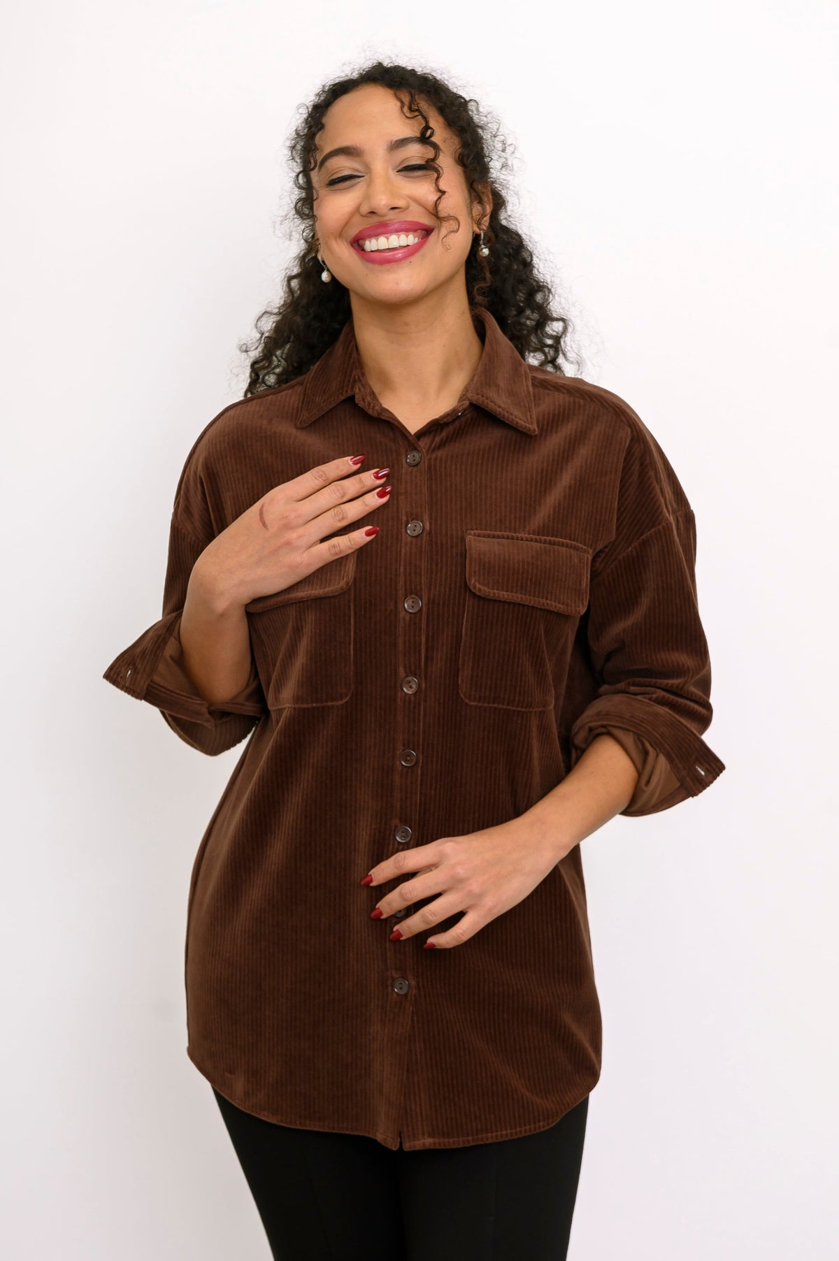 Front view of female model wearing a relaxed-fit brown cotton corduroy button-up jacket against white backdrop