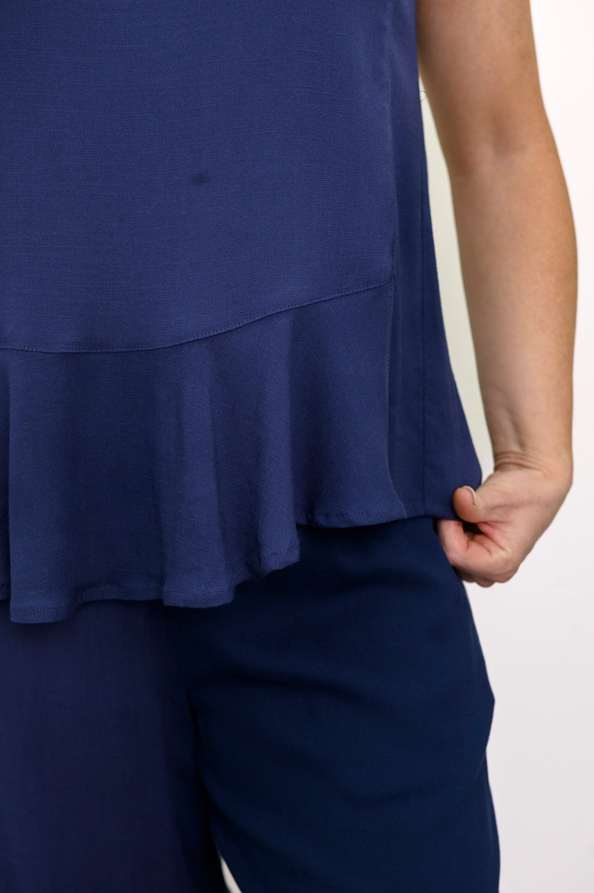 Front view of woman wearing a navy blue sleeveless top and navy blue pants on a white background