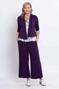 Model wearing purple watercolor peplum top underneath purple open cardigan and matching pants