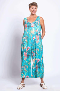 Woman with hands in pockets showing a turquoise jumpsuit with a floral print
