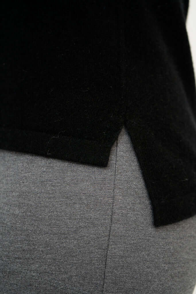 Close-up of hi-lo hemline detail on black sweater