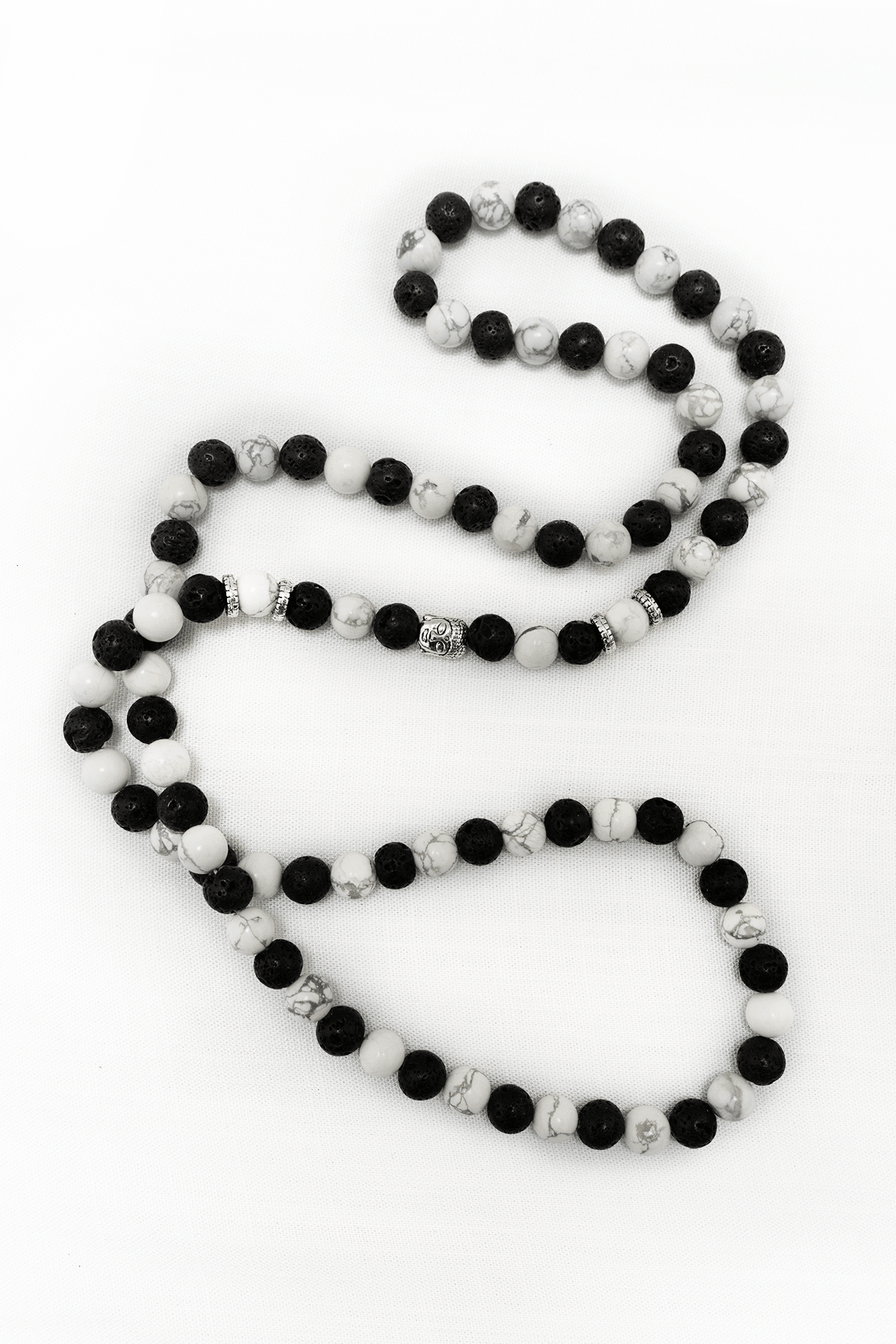 Howlite and lava stone meditation mala necklace with silver accent beads on a white background