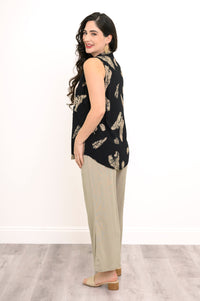Side view of woman smiling in leaf print top and beige wide-leg pants