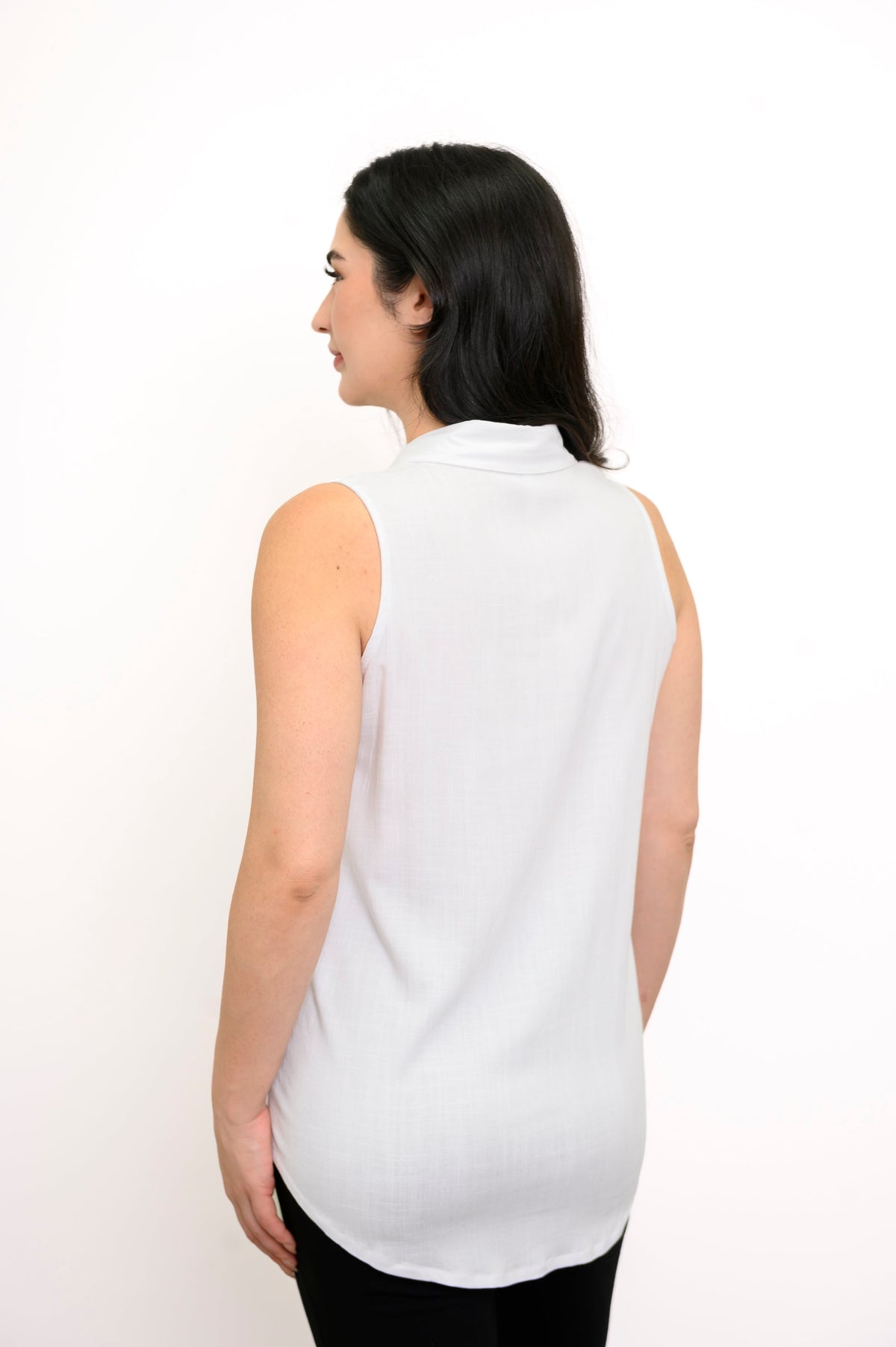 Back view of woman wearing white bamboo linen tank top and black pants