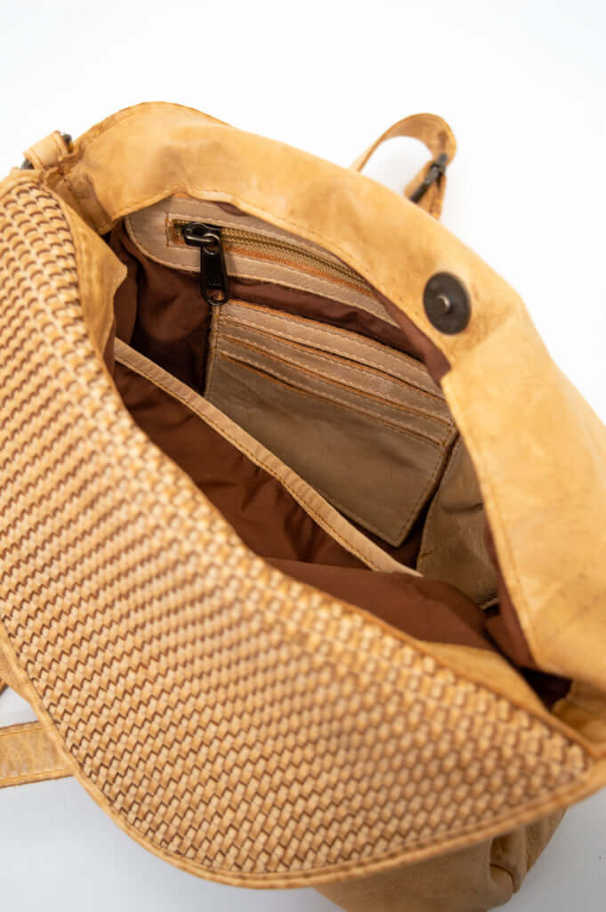 Inside compartments and pockets of tan woven flap crossbody bag