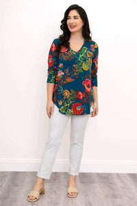 Woman smiling, wearing v-neck 3/4 sleeve bright floral print top and white pants
