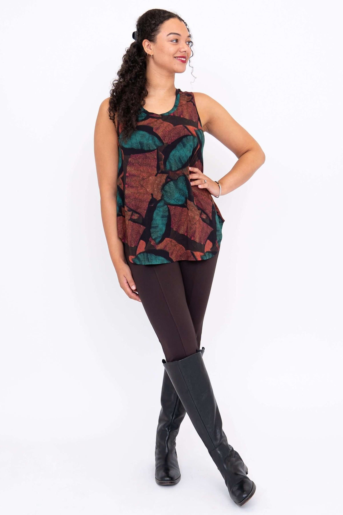 Model posing in sleeveless top with rounded hem, hand on hip, showing autumn leaf print