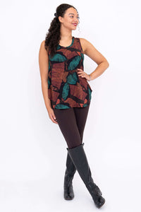 Model posing in sleeveless top with rounded hem, hand on hip, showing autumn leaf print