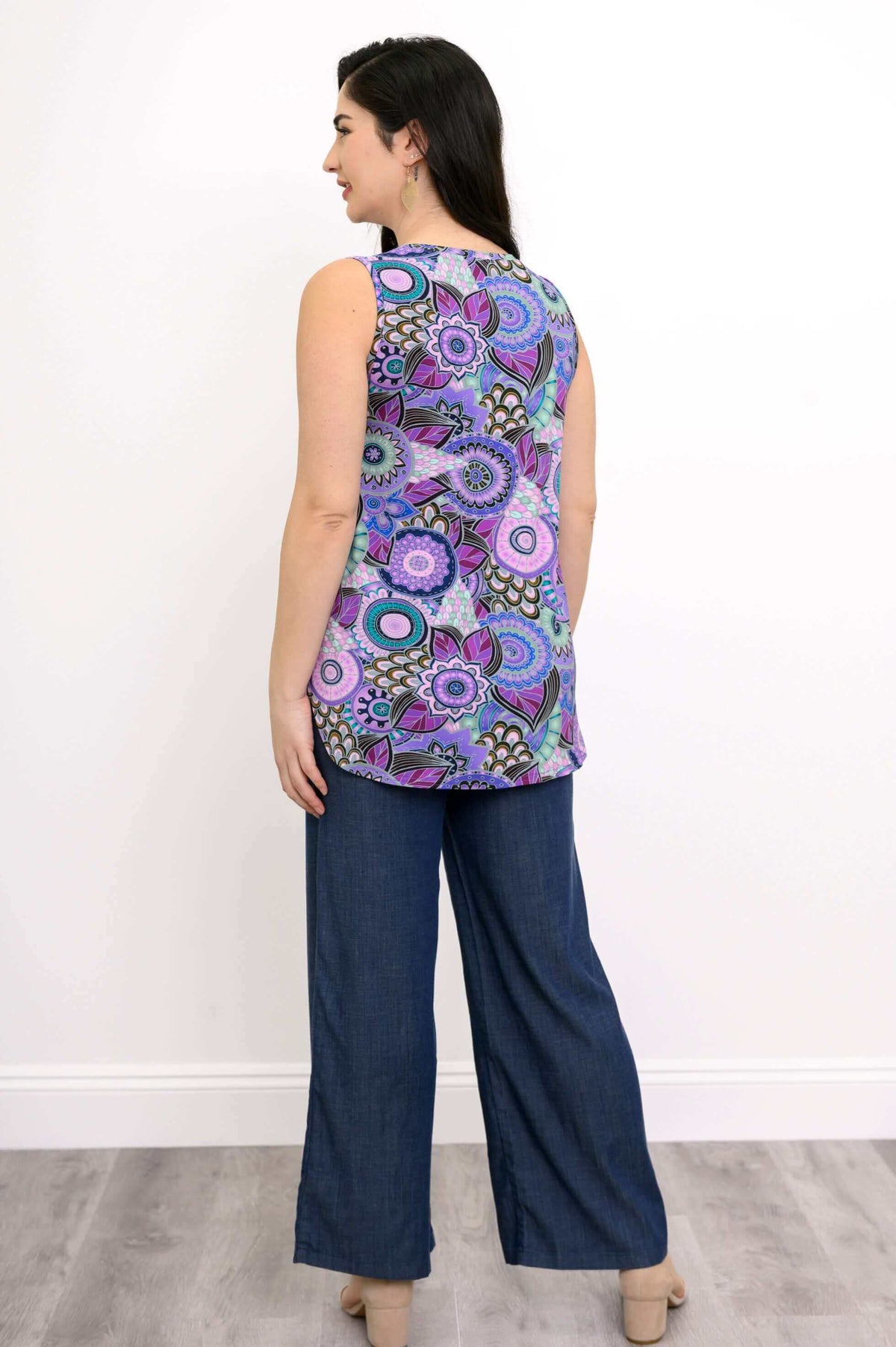 Full body back view of woman wearing sleeveless purple mandala patterned top and tencel denim pants
