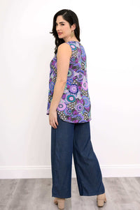 Side view of woman modelling sleeveless purple patterned top and blue denim pants