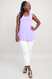 Full body view of woman wearing sleeveless lilac tank with rounded hem and white pants