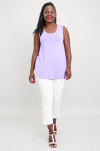 Front view of woman smiling in lavender round neck tank, white pants, and white sandals