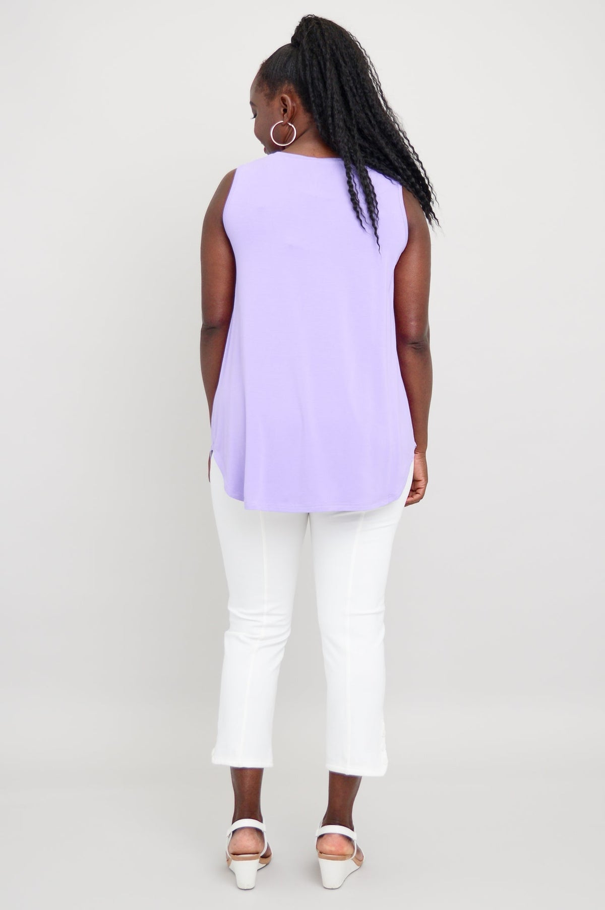 Back view of woman wearing lavender sleeveless tank with rounded hem and relaxed fit