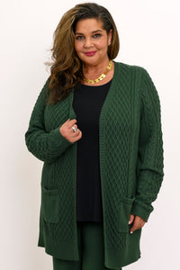 Front view of a woman wearing a forest green open cable knit cardigan sweater over a black top.