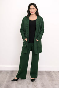 Woman modeling a dark green open front knit cardigan with patch pockets and matching trousers.