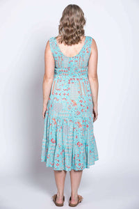 Back view of woman in blue tiered sleeveless dress with red floral print